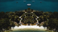 an aerial view of a tropical island with boats in the water